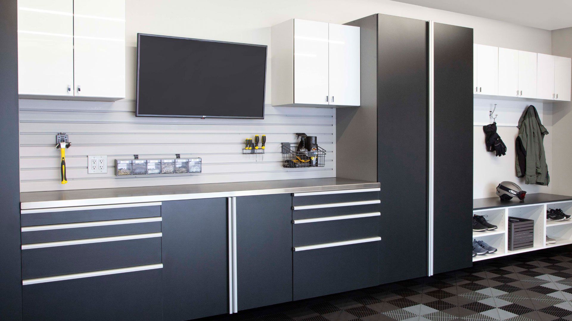 A garage with black and white cabinets and a flat screen tv on the wall.