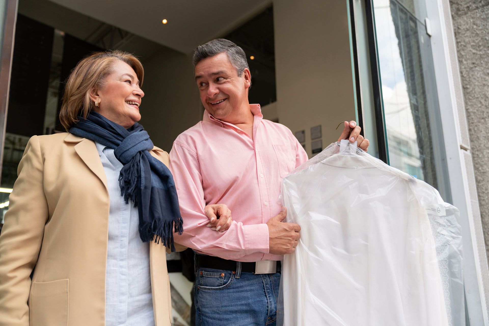Couple Holding Dry Cleaned Clothes — Beatrice, NE — Soap Opera Laundry