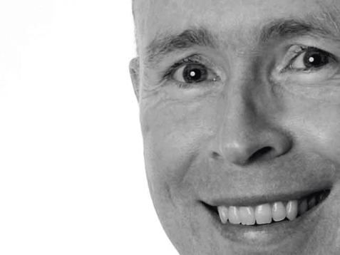 A close up of a man 's face smiling in a black and white photo.