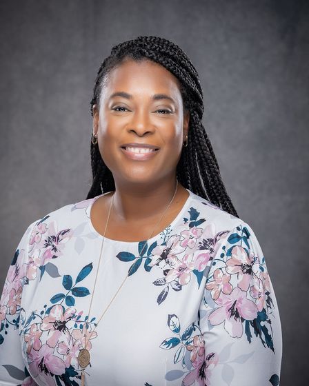 A woman in a floral shirt is smiling for the camera.