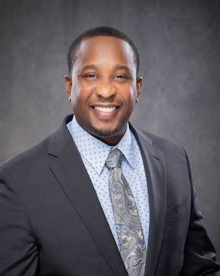 A man in a suit and tie is smiling for the camera