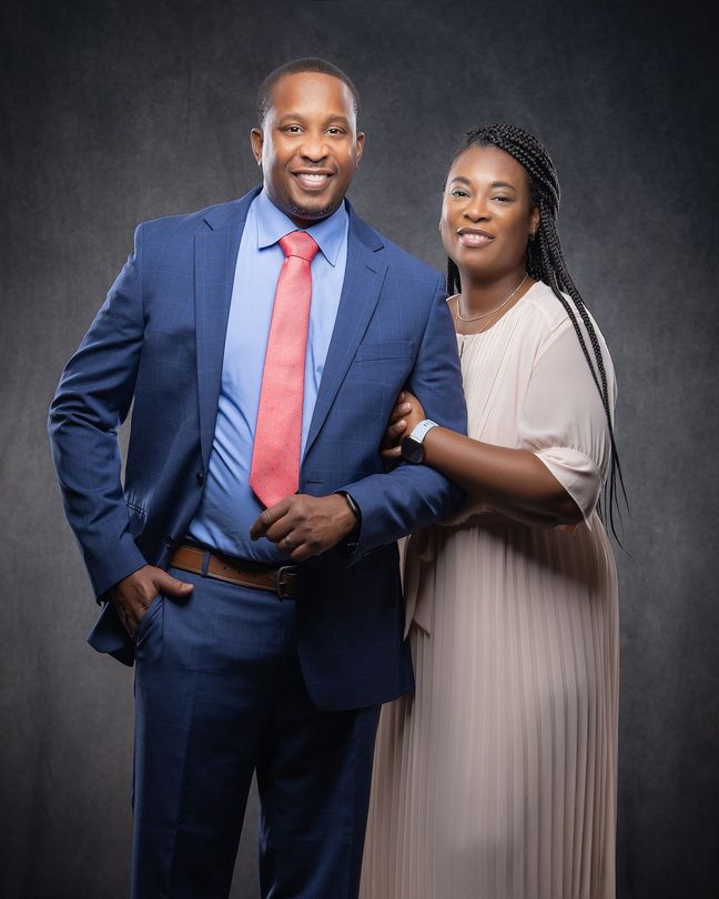 A man in a suit and tie is standing next to a woman in a white dress.