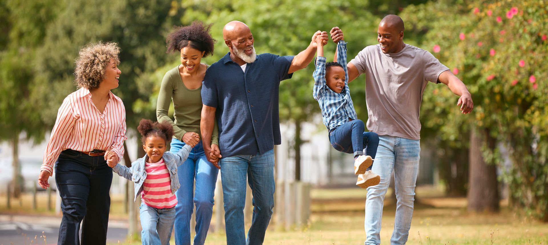 A group of people are walking in a park holding hands.