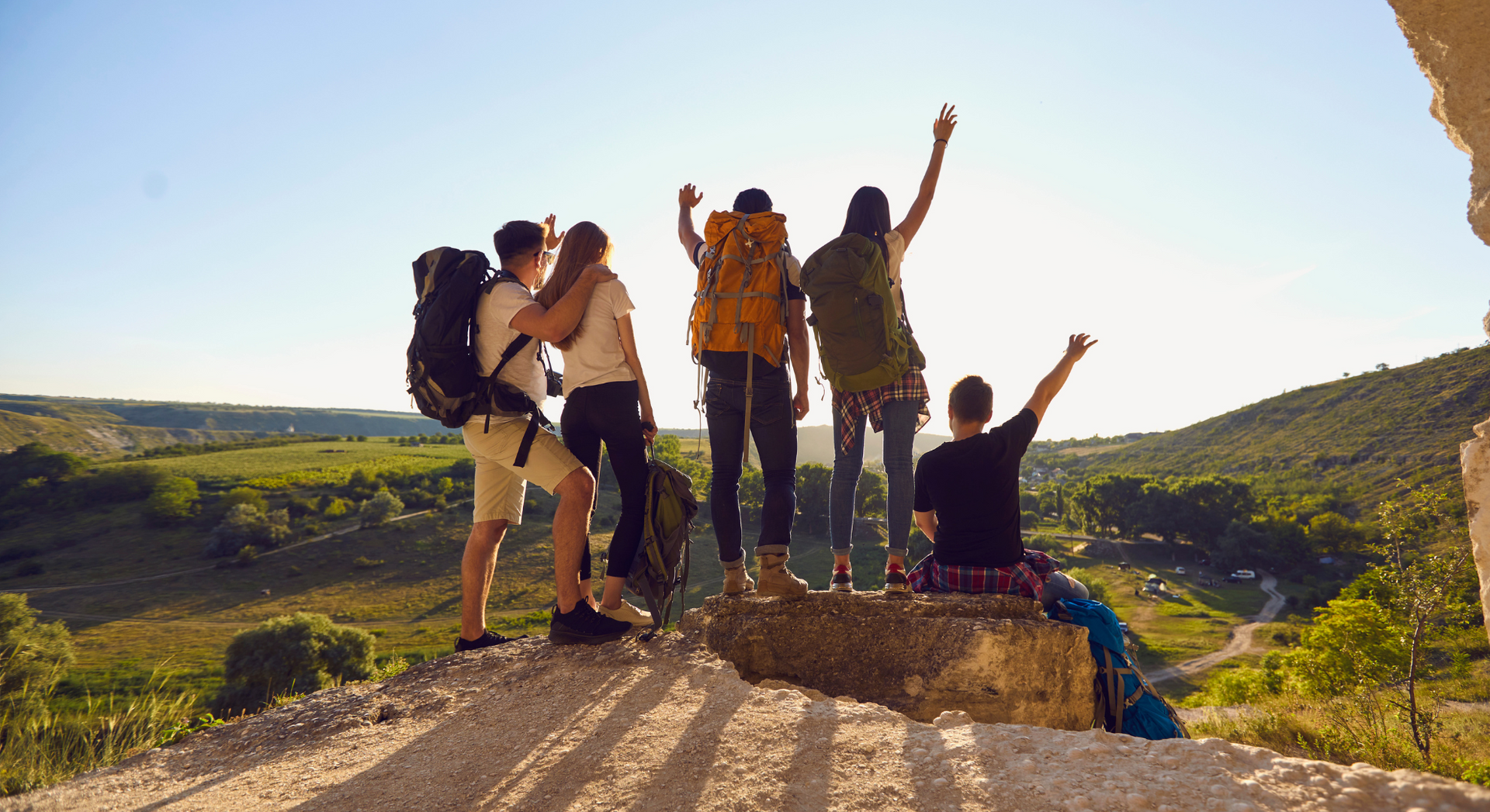 A group of people with backpacks are standing on top of a mountain.