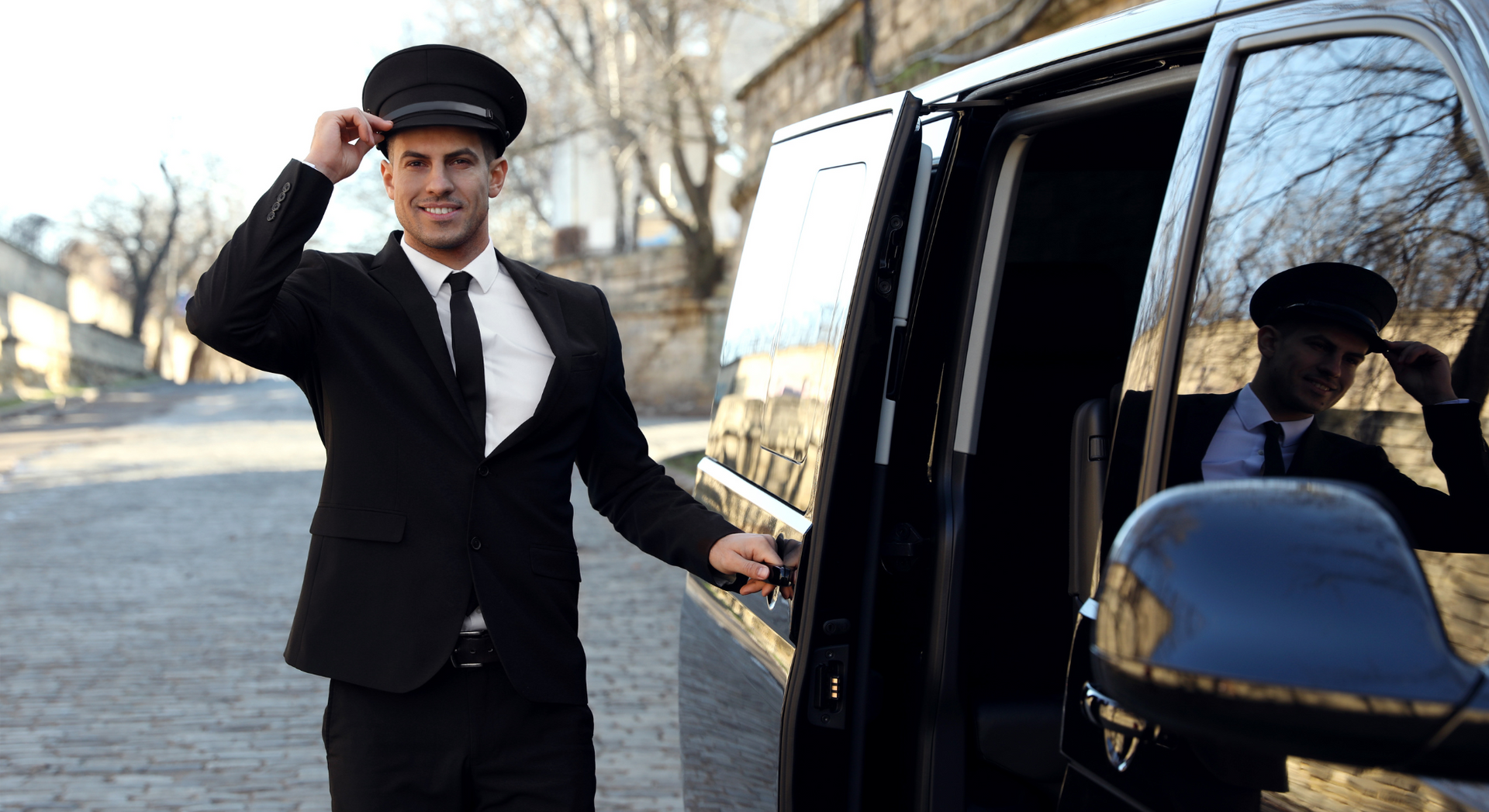 A man in a suit and tie is standing next to a limousine.