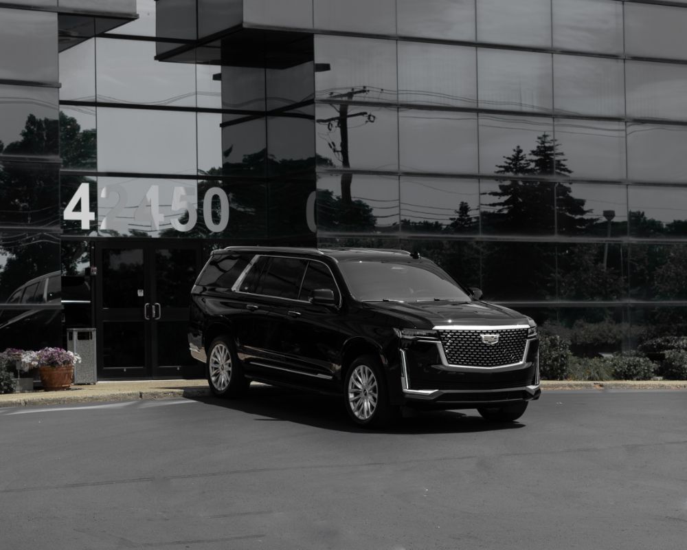 A black cadillac escalade is parked in front of a building.
