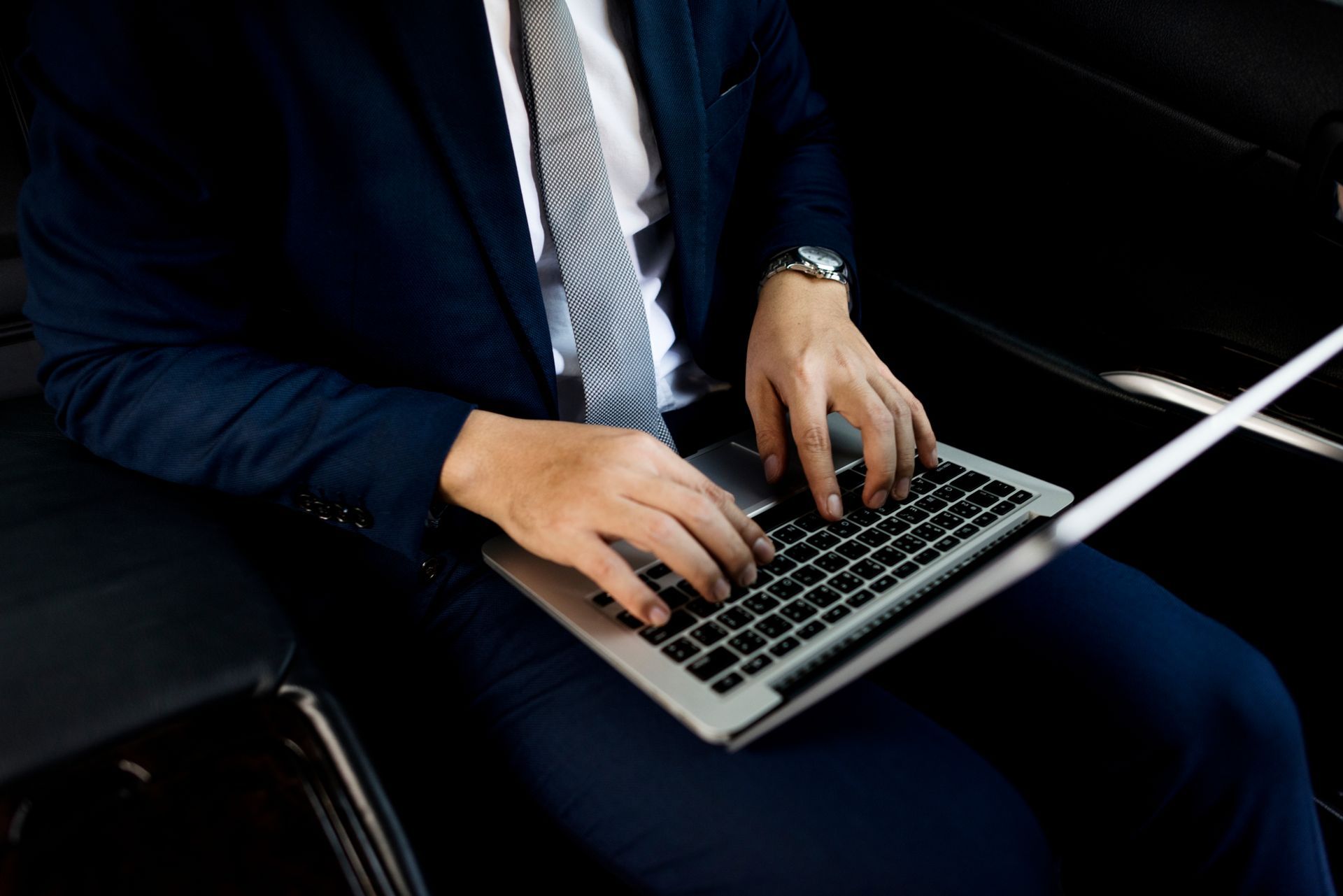 A man in a suit and tie is typing on a laptop computer.