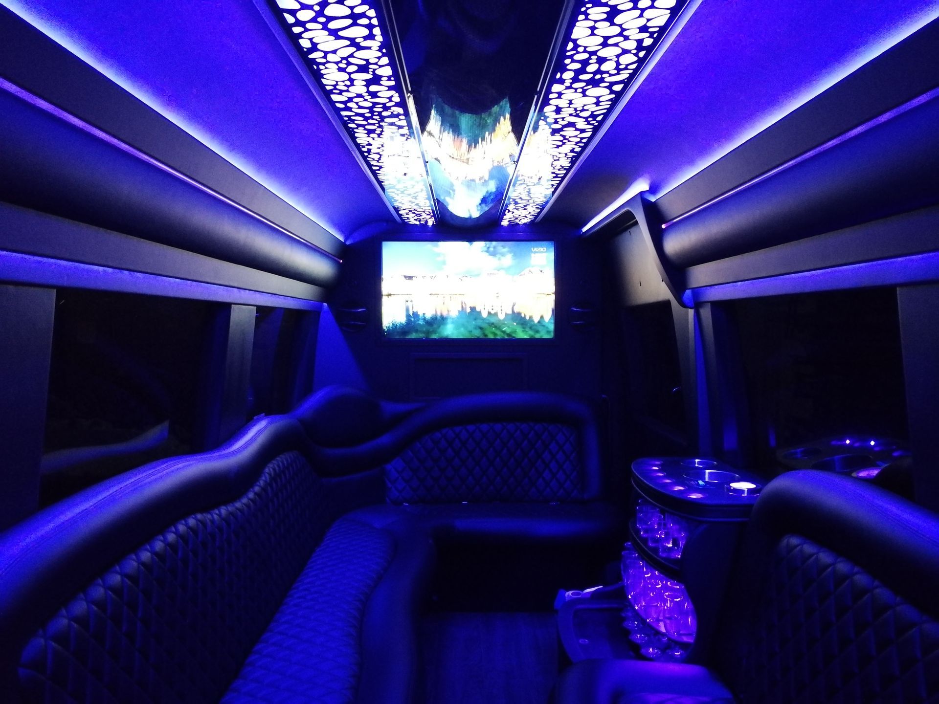 The inside of a limousine with a tv on the ceiling