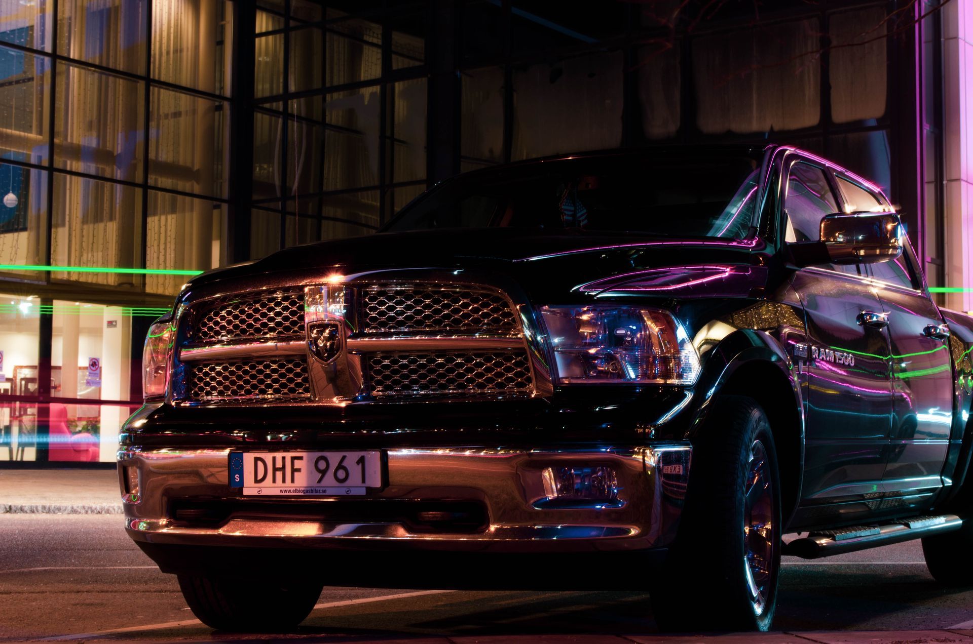 A black dodge ram truck is parked in front of a building at night.