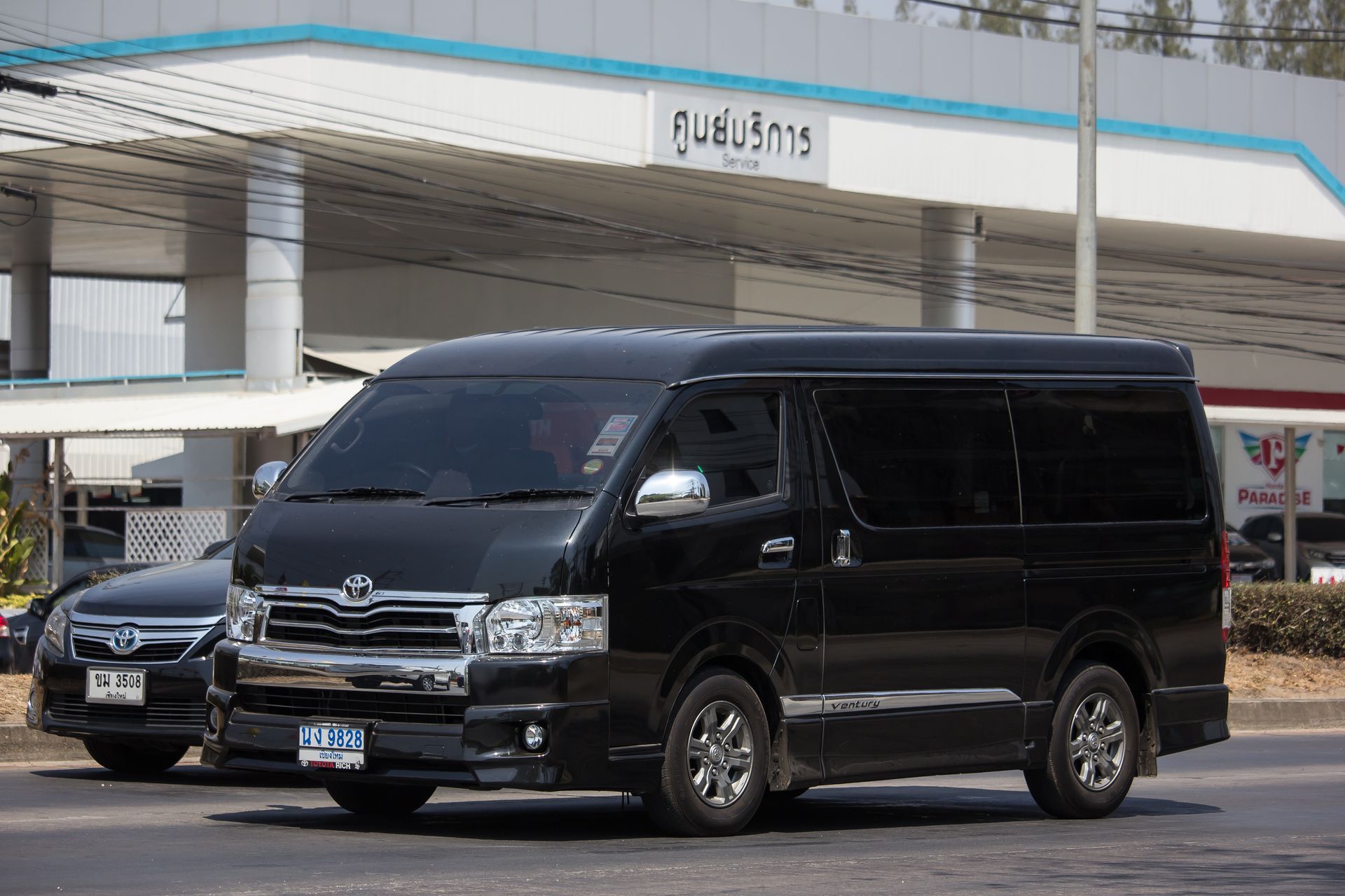 A black van is parked in front of a gas station.