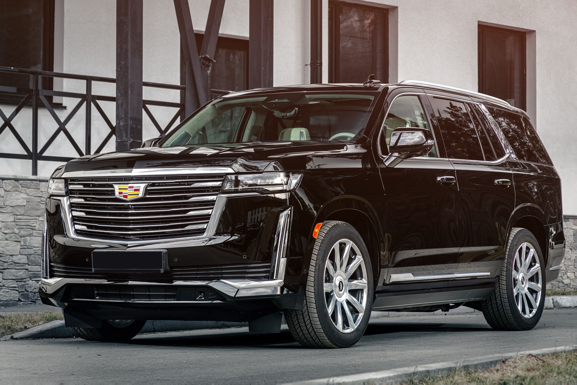 A black cadillac escalade is parked on the side of the road in front of a building.