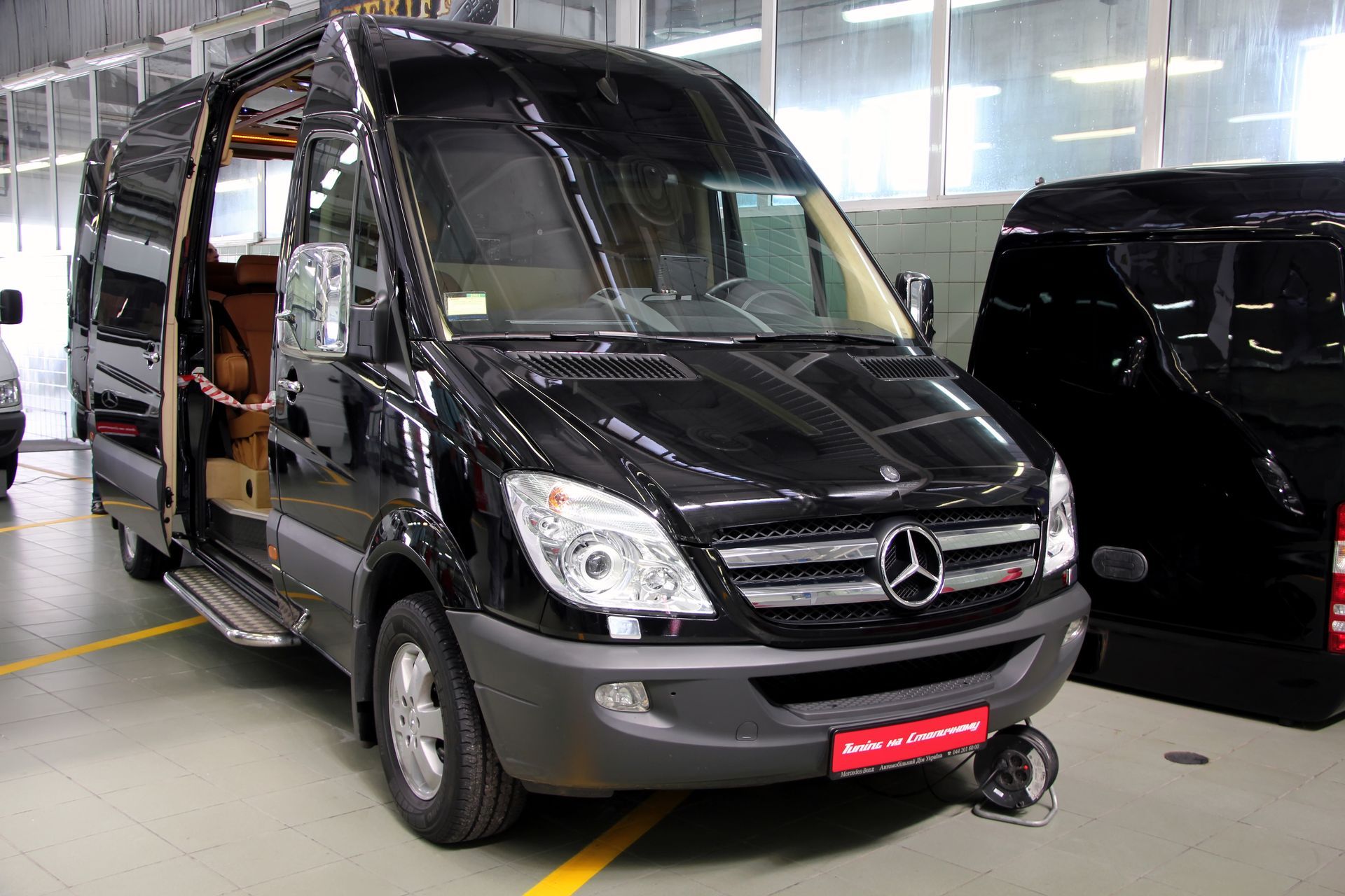 A black mercedes van is parked in a garage.