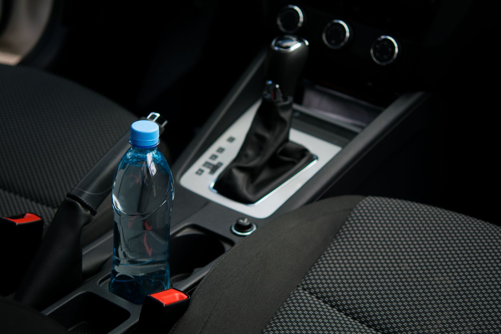 A bottle of water is in the center console of a car.