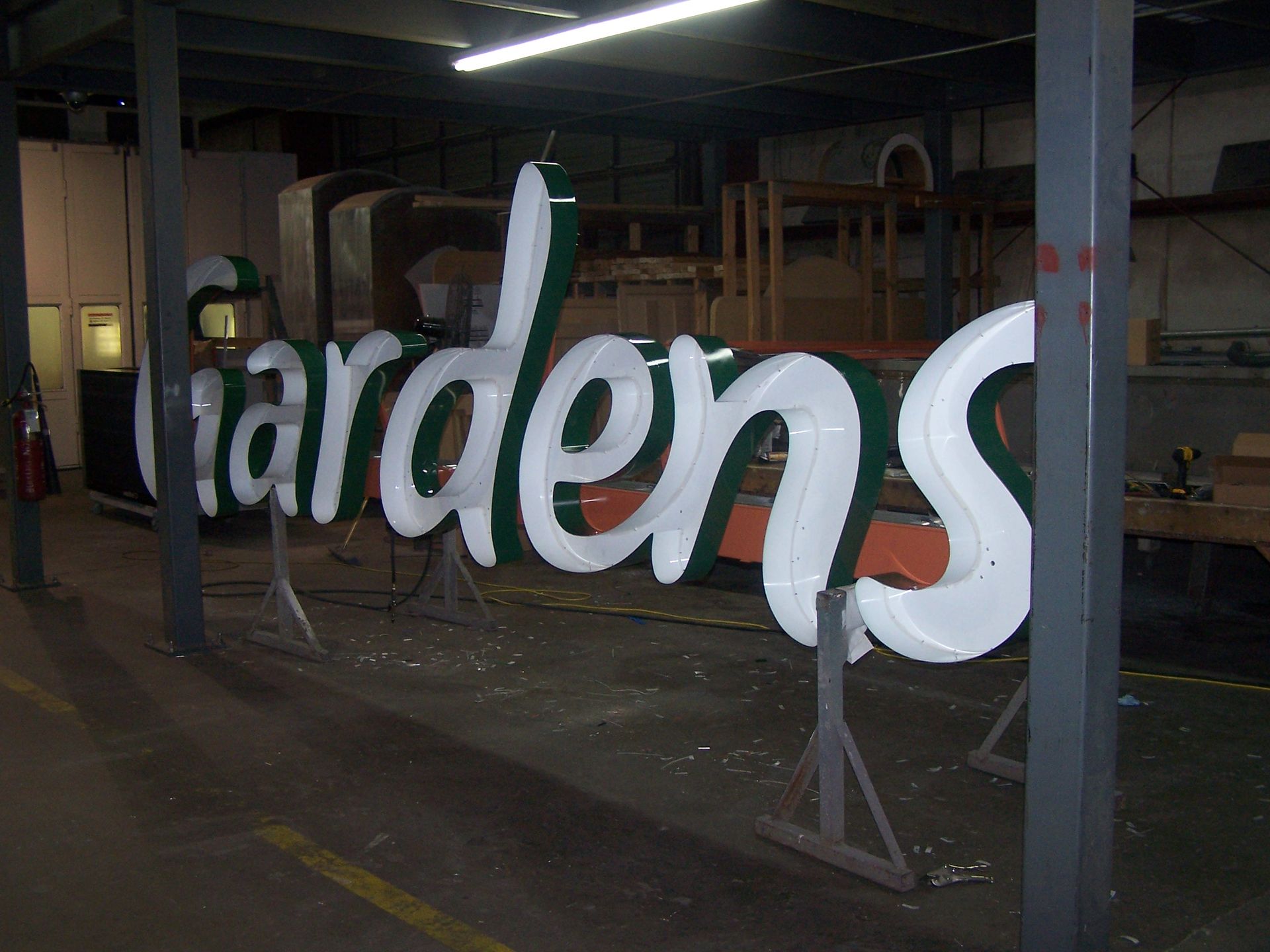 A sign that says gardens is in a warehouse