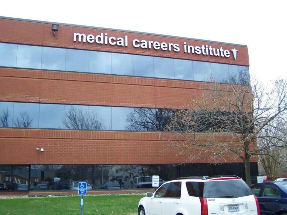A white suv is parked in front of a medical careers institute building