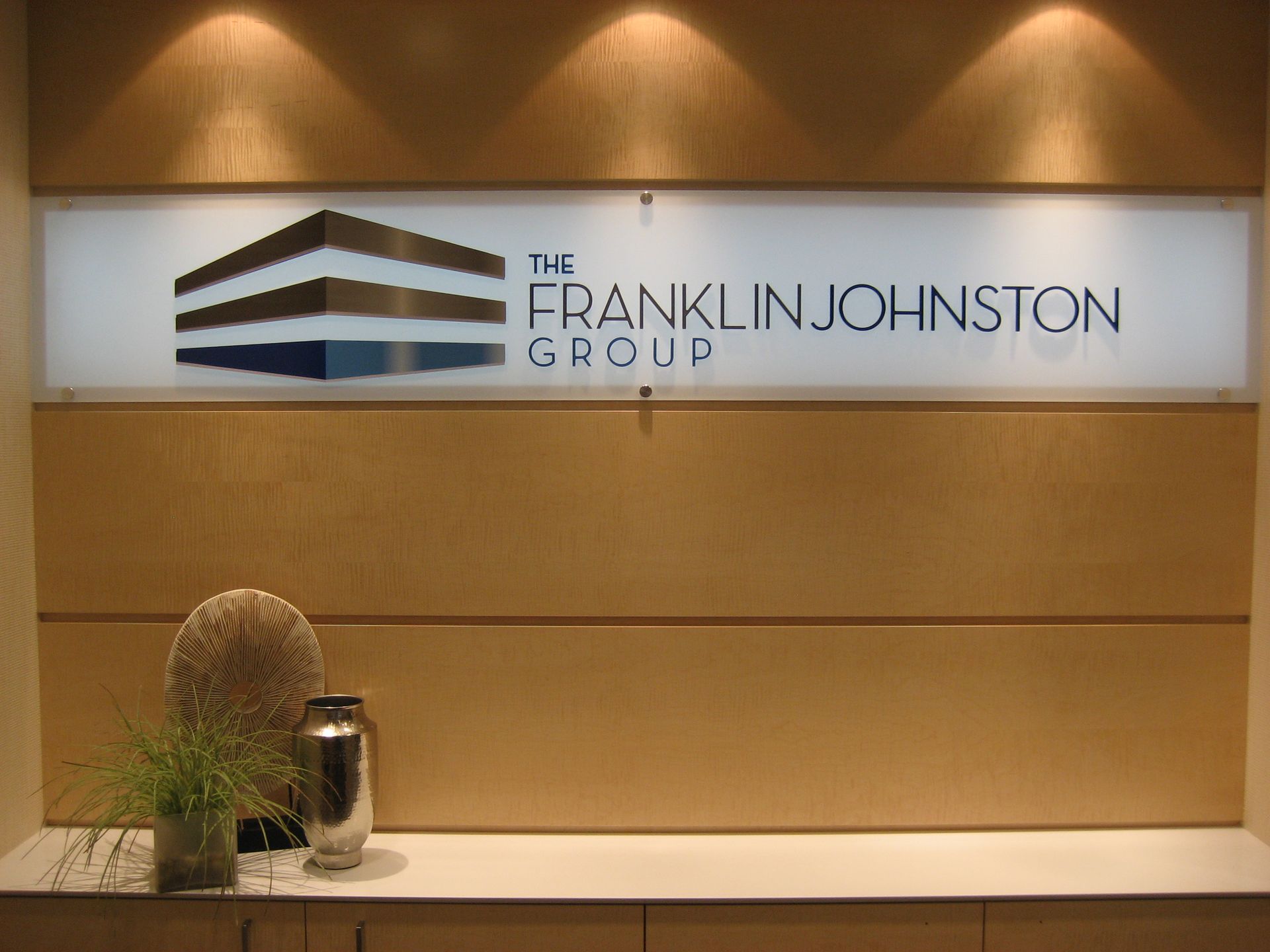A sign for the franklin johnston group hangs on a wall