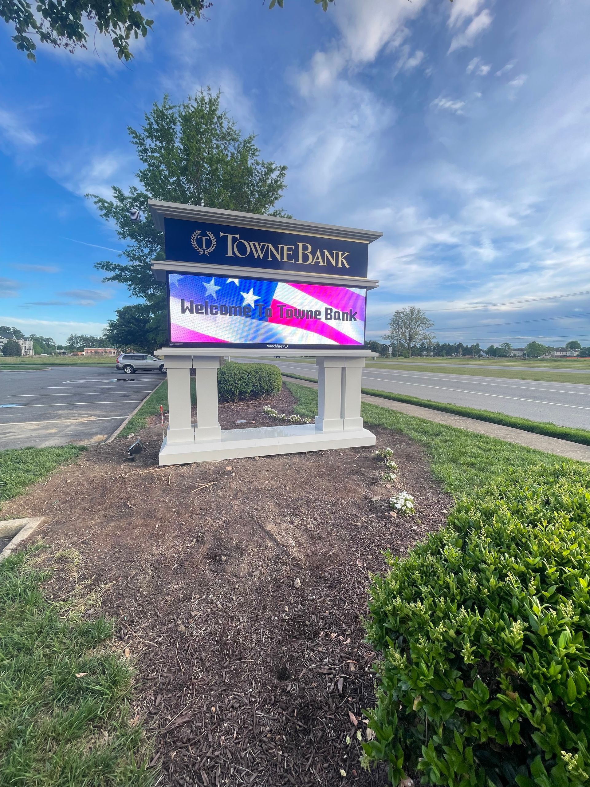 A large sign with an american flag on it is sitting on the side of a road.