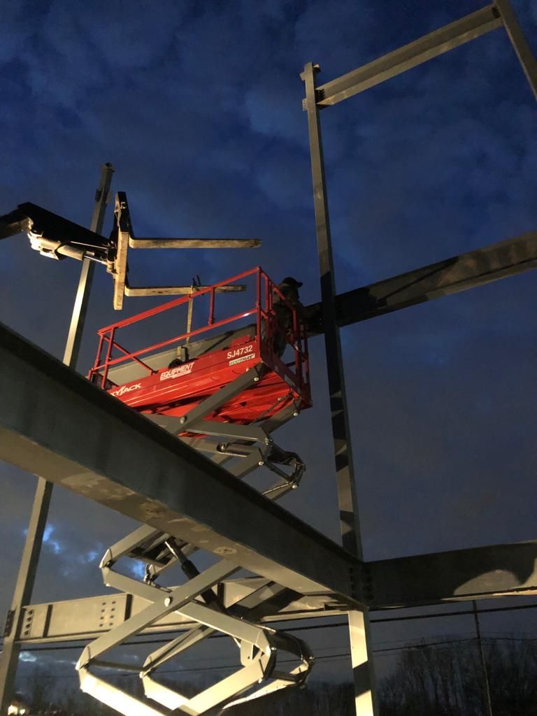 A red scissor lift is sitting on top of a metal structure.