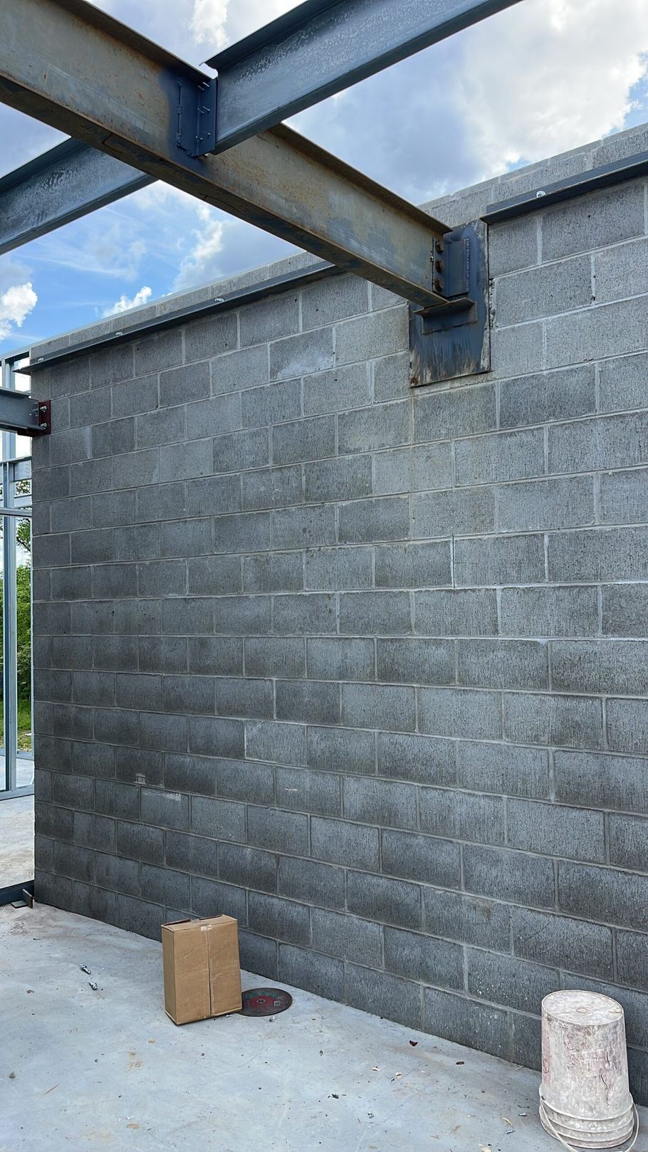 A brick wall with a metal structure behind it is under construction.