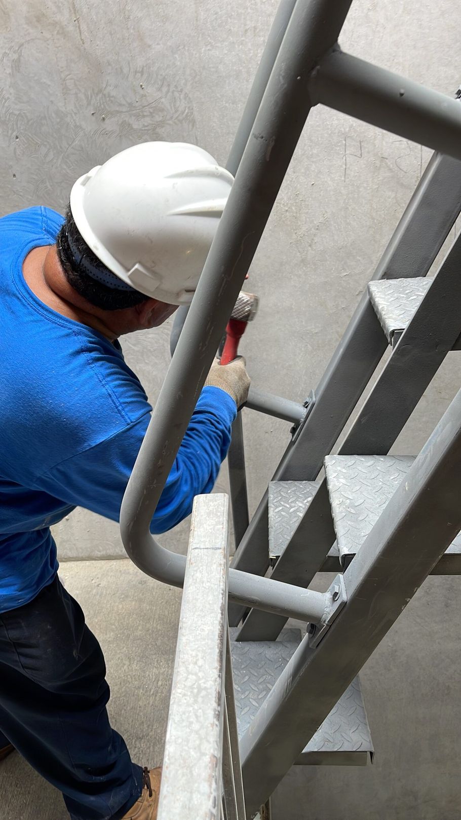 A man wearing a hard hat is working on a set of stairs