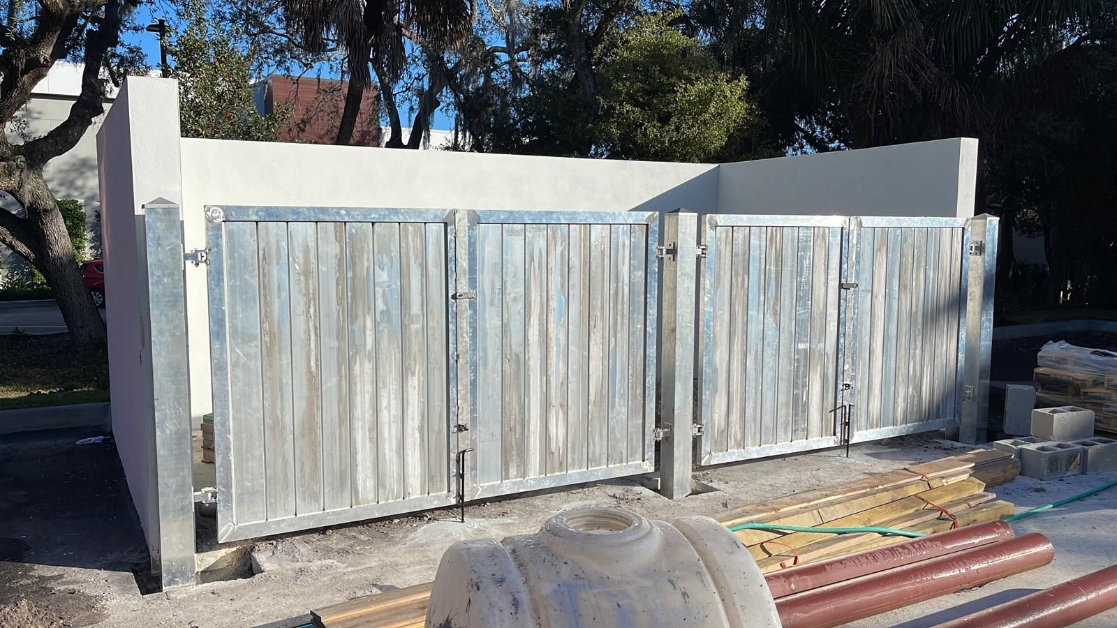 A wooden fence is being built next to a white wall.