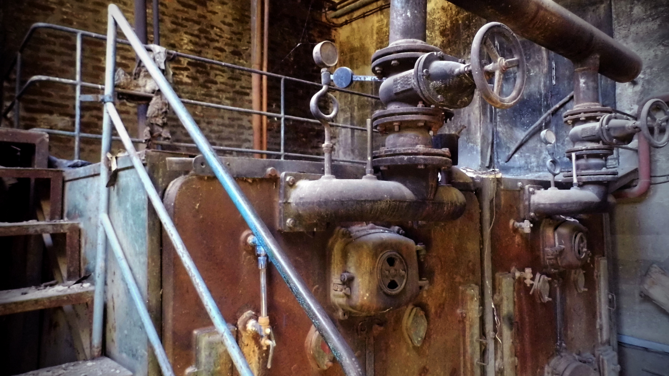There are a lot of pipes and valves on the wall.