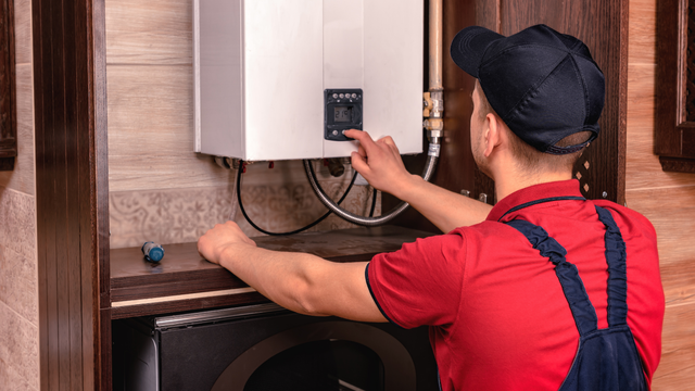A man is fixing a water heater in a kitchen.