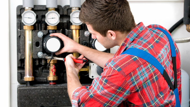 A man in a plaid shirt is working on a machine.