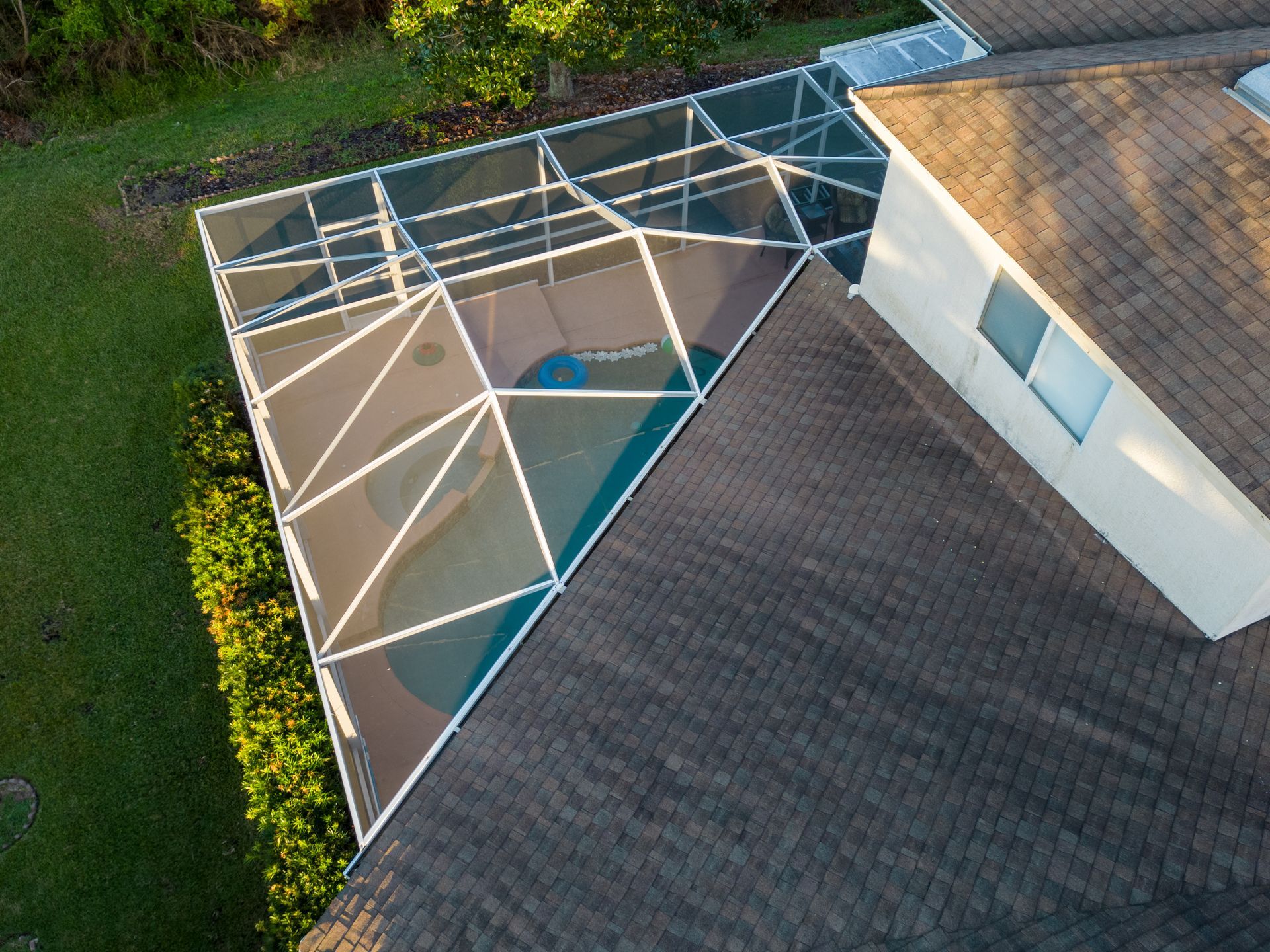 Upper view of a screened patio enclosure with a pool, connected to a home.