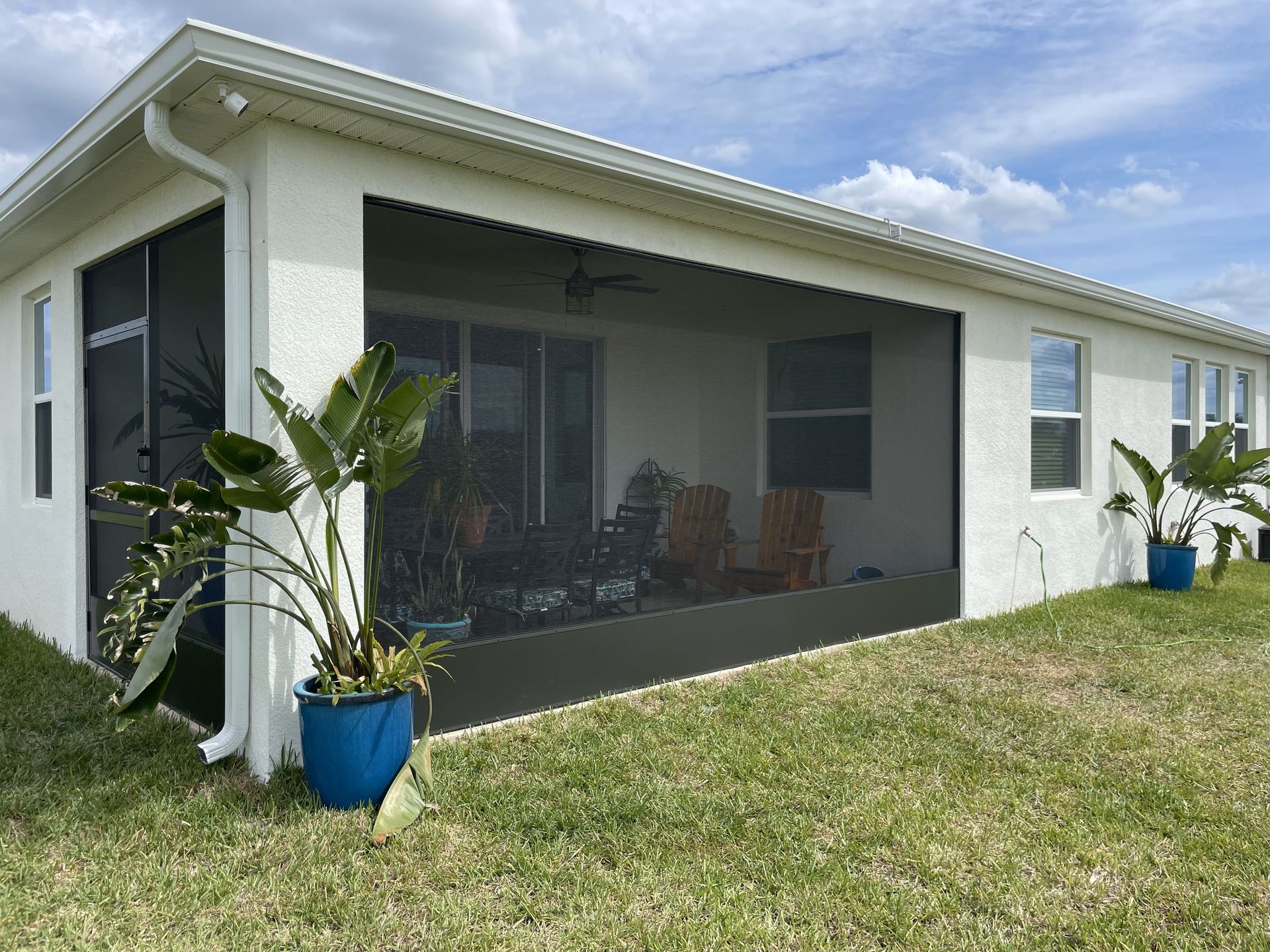 A white house with a Screened-in porch and potted plants in front of it – Valrico, FL - Salco Screens