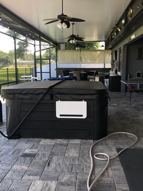 A black hot tub is sitting under a ceiling fan on a patio – Valrico, FL - Salco Screens