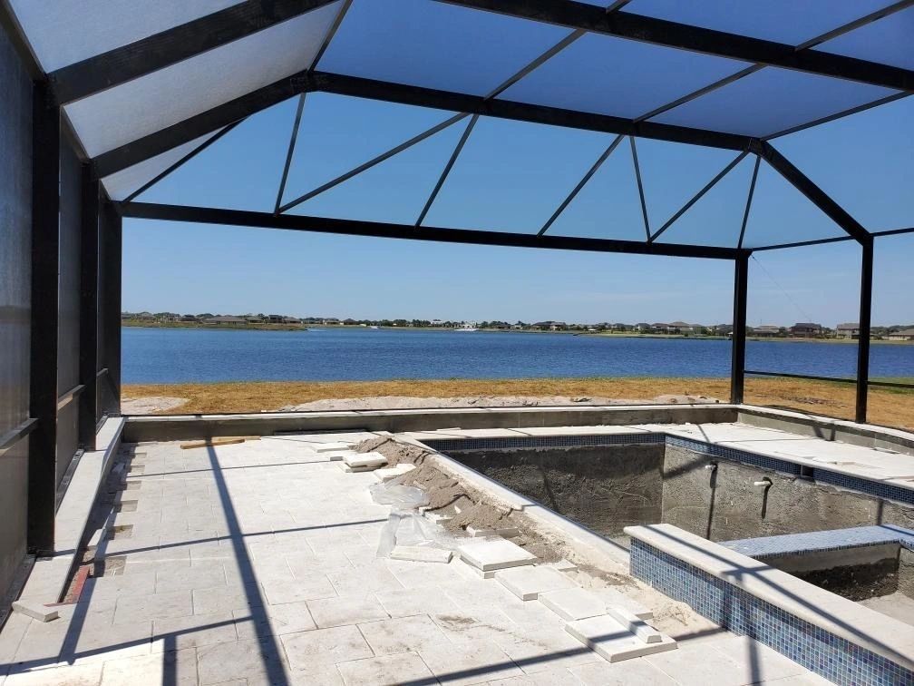 A swimming pool under construction with a view of a lake – Valrico, FL - Salco Screens