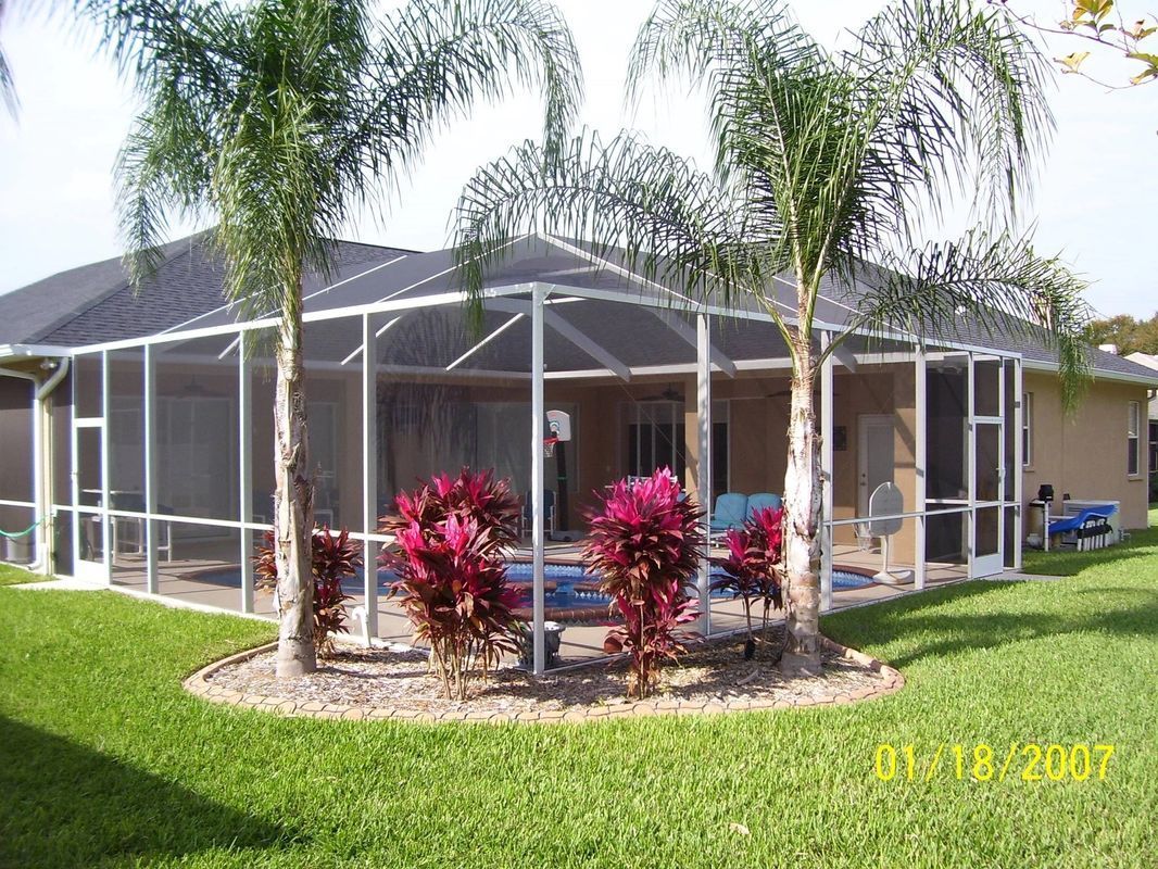 A Screened-in area with palm trees in front of a house – Valrico, FL - Salco Screens