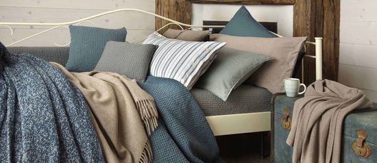 un letto in ferro coperto di lenzuola e cuscini grigi
