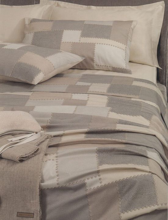 un letto con biancheria a quadroni beige e grigio