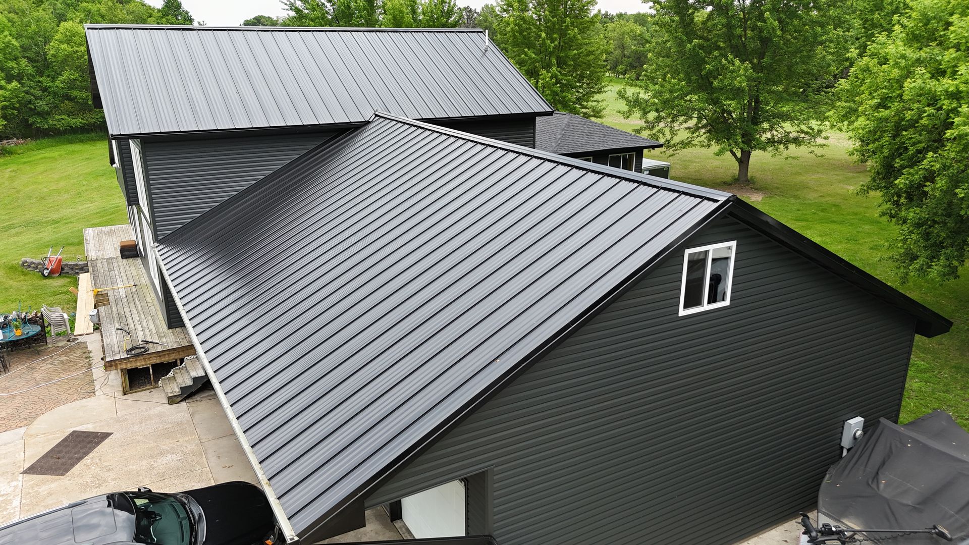 Exterior view of a beige house with a small green bush and a dark brown door, under a bright blue sky.