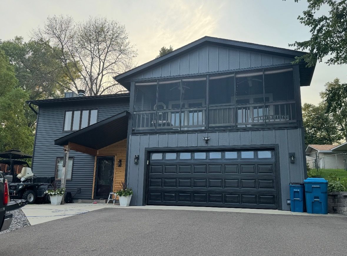 Roofers working on a house roof, surrounded by supplies, on a sunny day.