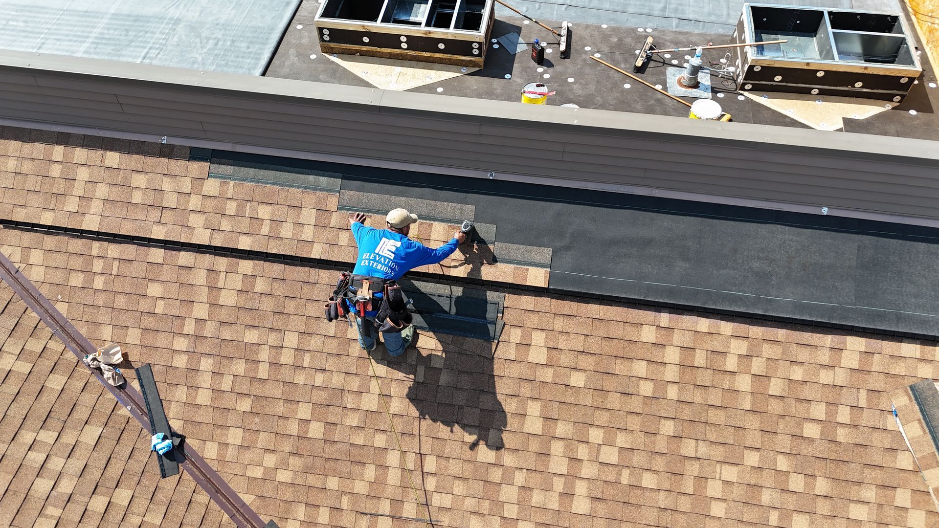 Two-story house with brown siding, white garage door, and a green lawn.