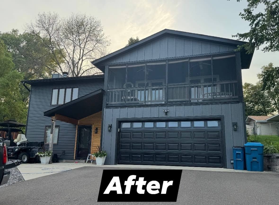 House exterior after renovation, painted dark gray with black garage door and screened balcony.