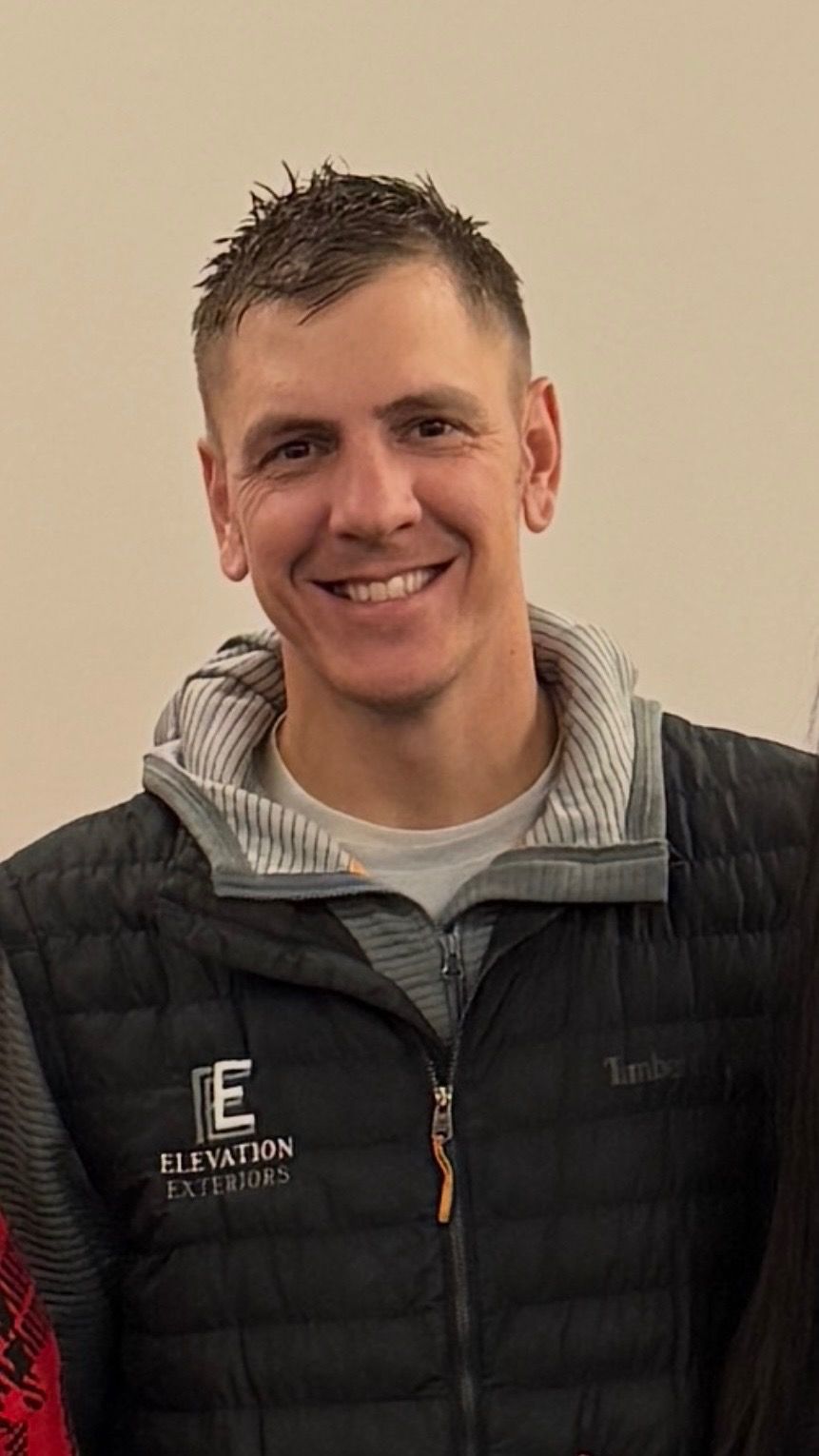 Man with arms crossed smiling in front of 