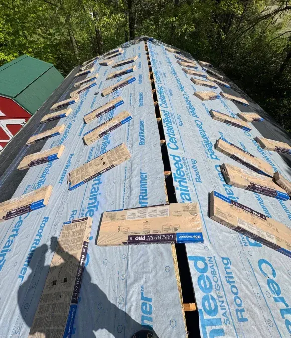 New roof under construction with blue underlayment and wooden shims.