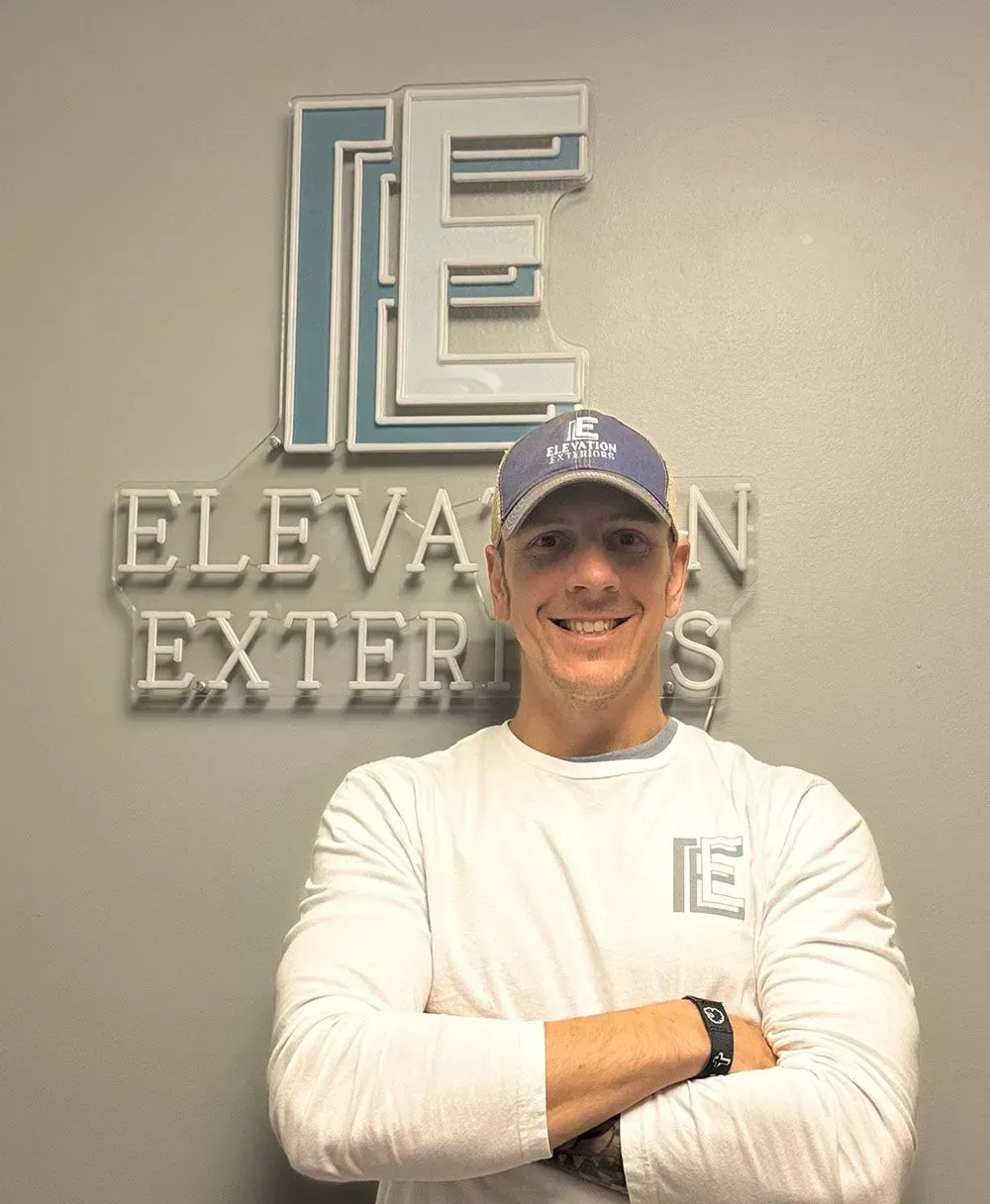 Man with arms crossed smiling in front of