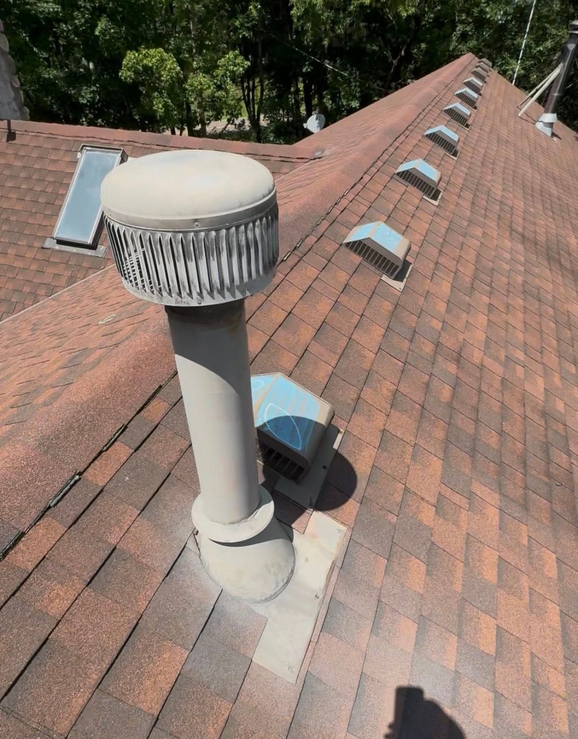 Brown shingled roof with a large, cylindrical vent and smaller vents.