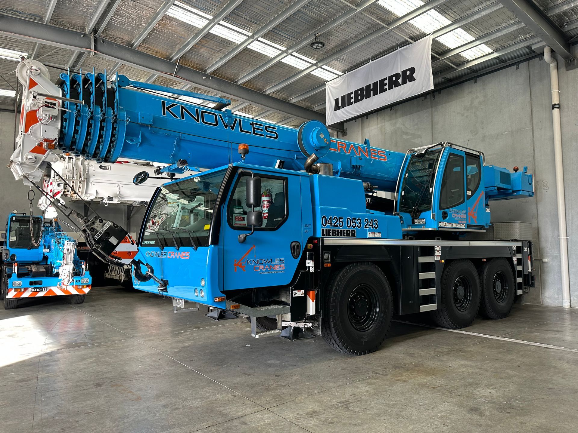 Liebherr all-terrain crane from Knowles Cranes parked inside warehouse under LIEBHERR banner.