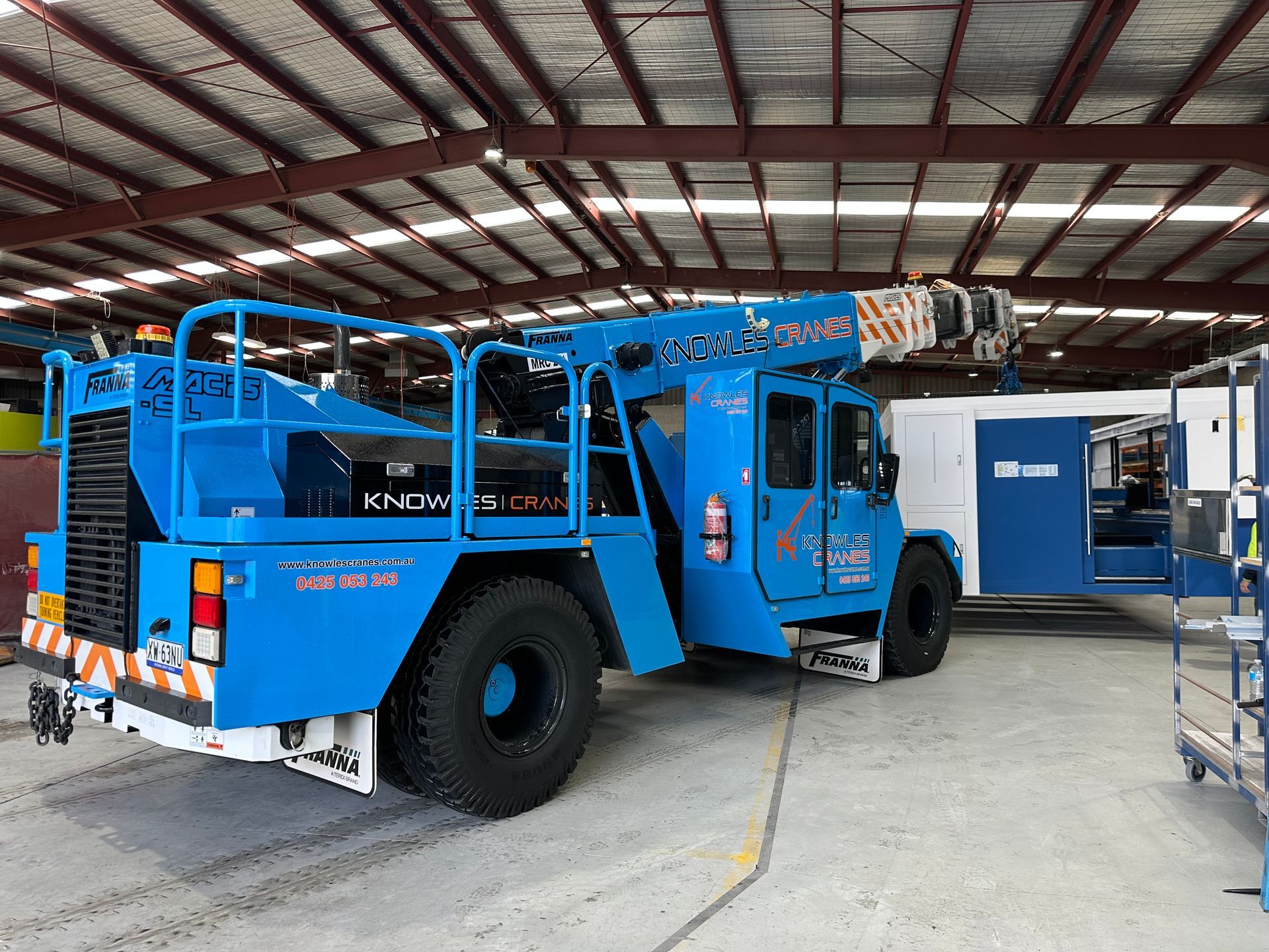 Franna MAC 25 crane lifting modular building unit inside an industrial warehouse.
