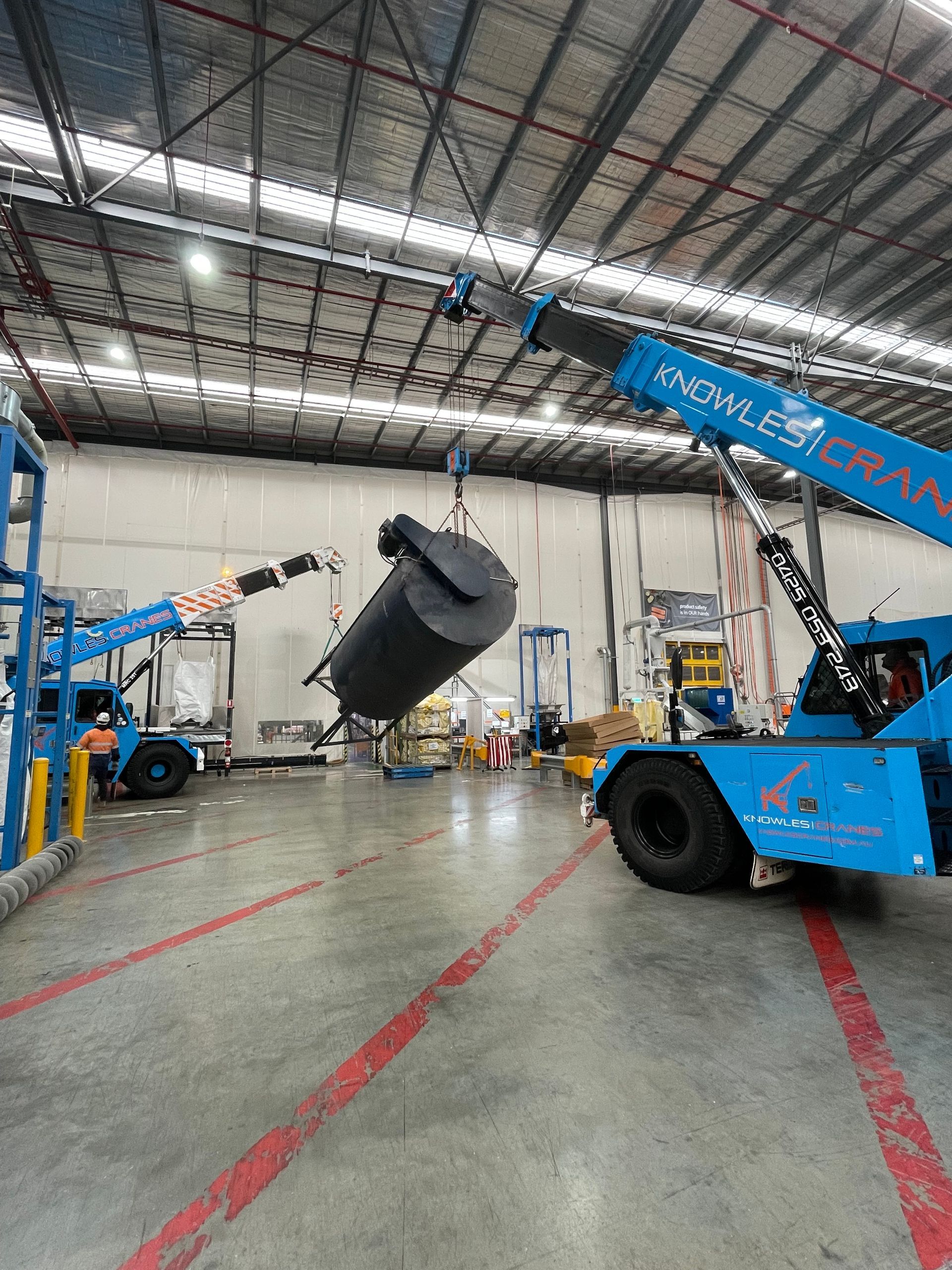 A crane is lifting a large object in a warehouse.