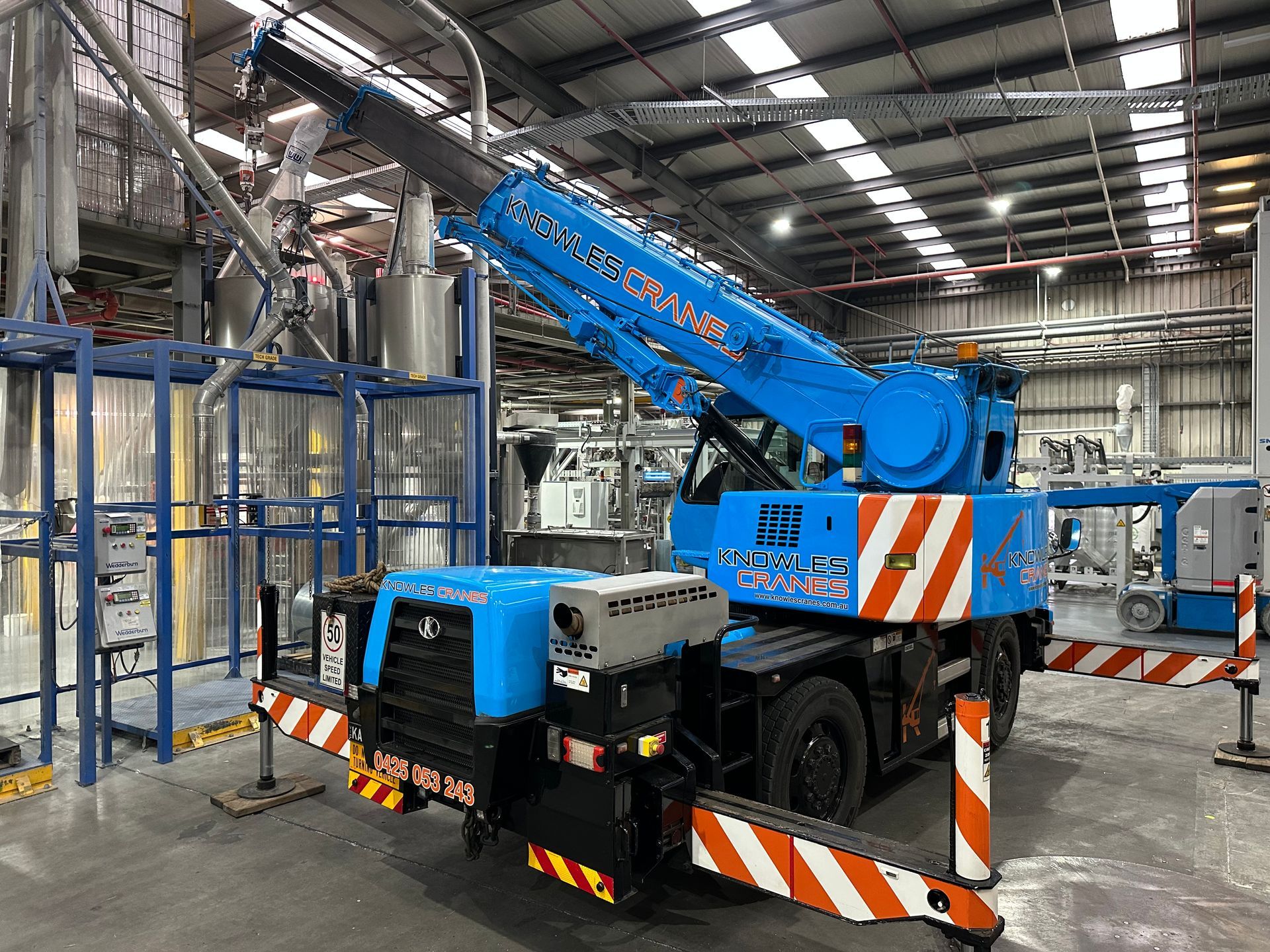Compact Kato crane navigating tight factory spaces to position equipment safely and efficiently