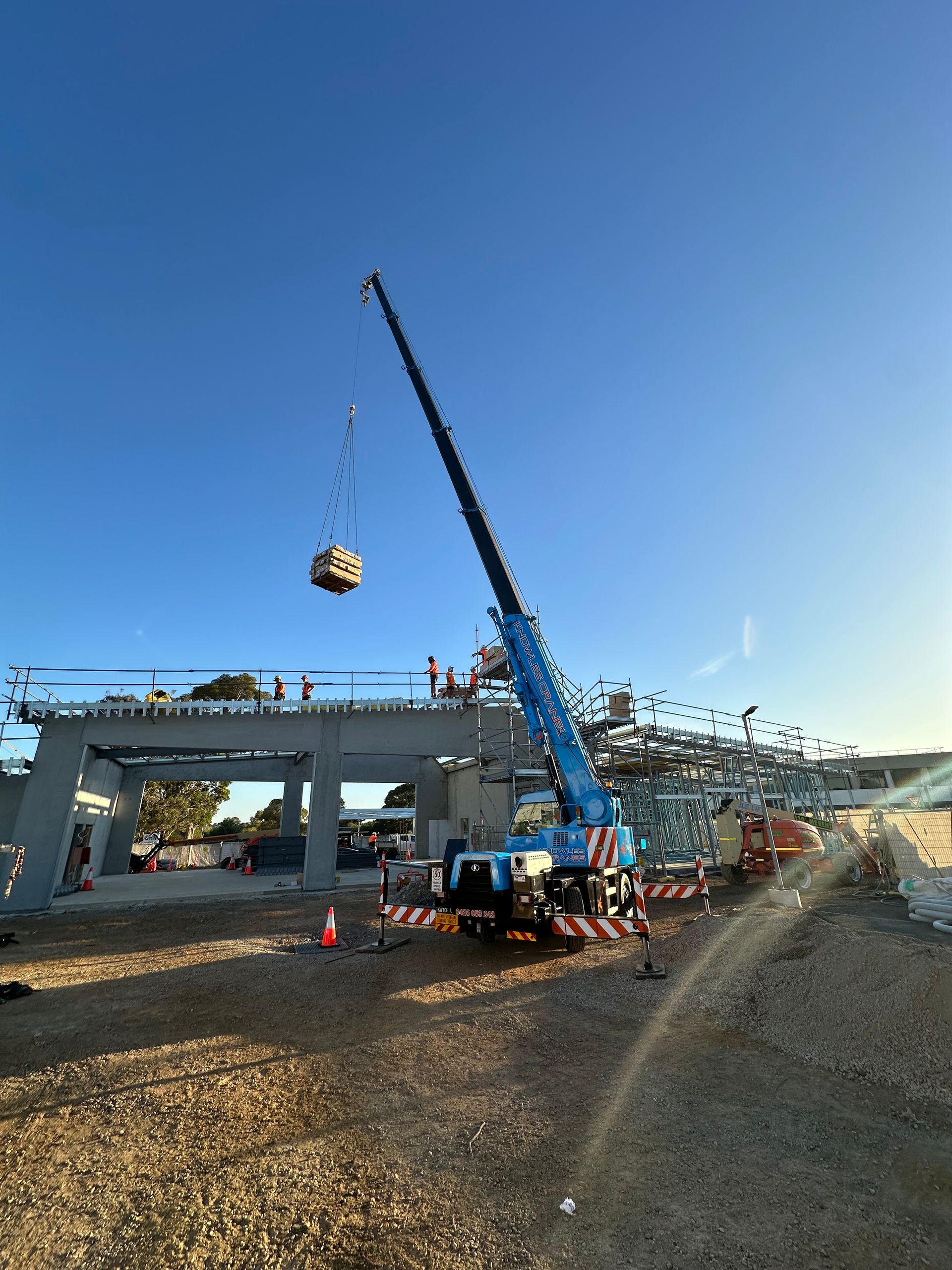 Mobile crane lifting heavy pallets for elevated construction framework assembly