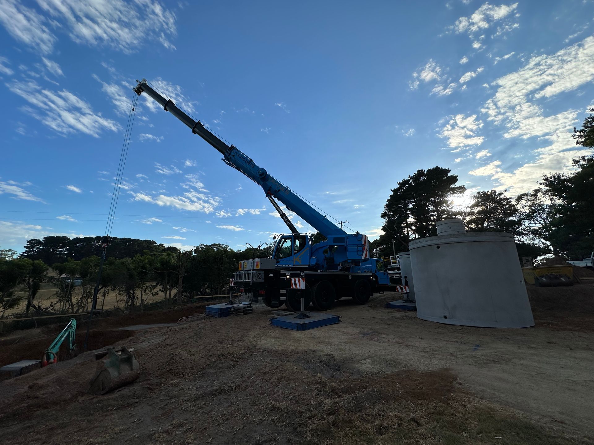 Mobile crane operating on a rural construction site during daylight.