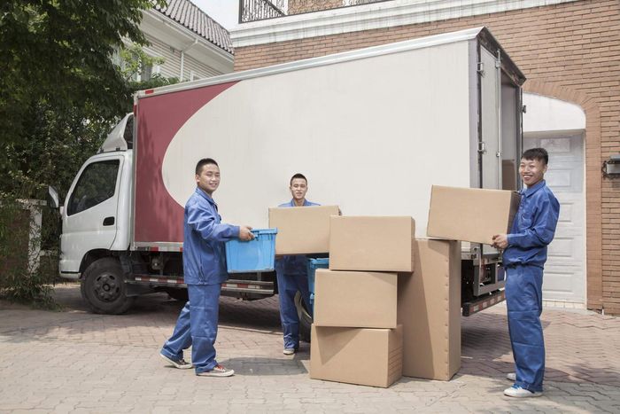 three men unloading boxes from a moving truck